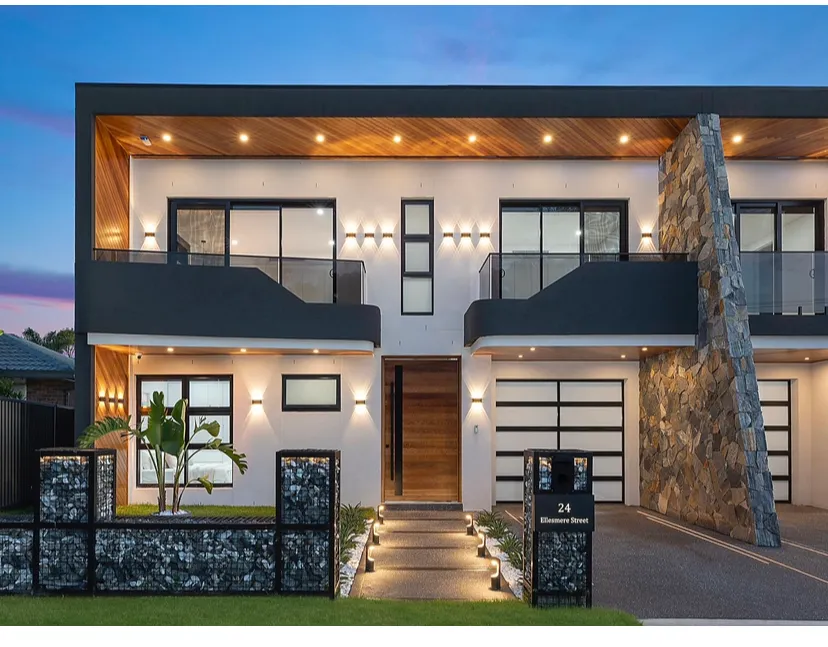 Modern duplex with timber soffits, stone feature wall and glass balustrades, photographed at completion.